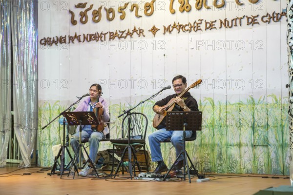 Musicians performing on a lighted stage at the night market in downtown Chiang Rai, Thailand