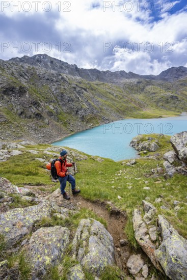 Mountaineers on a hiking trail, view of light blue mountain lake Trüber See in barren mountain