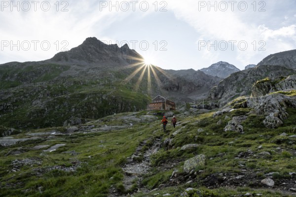 Mountaineer in front of mountain hut Elberfelderhütte with rocky mountain landscape, sun star in