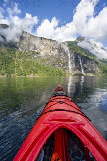 Kayak trip on the Geirangerfjord with waterfall The Seven Sisters, tip of a red kayak in the fjord,