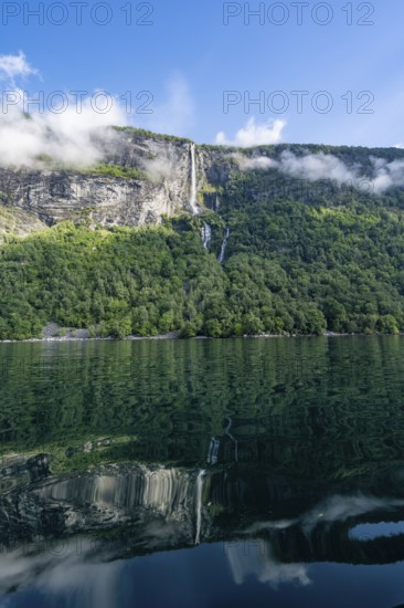 Atmospheric fjord landscape with Gjerdefossen waterfall, on the Geirangerfjord with reflection,