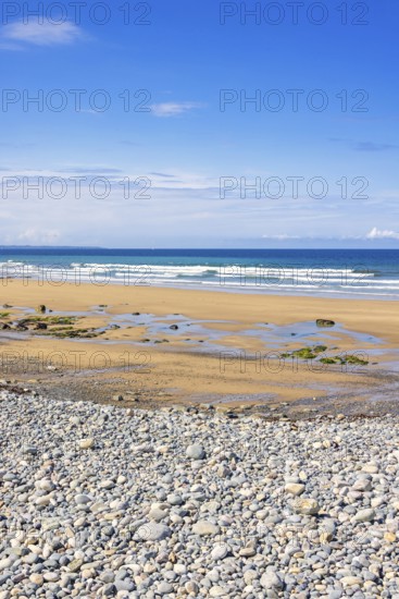 Pebble beach by the sea with a seascape view to the horizon and breaking waves on the shore a sunny