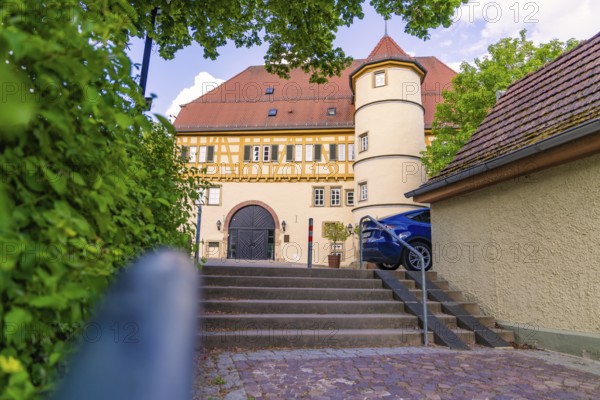 Half-timbered house with courtyard, stairs and parked car, surrounded by trees, Deufringen,
