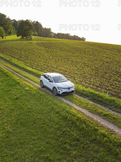 Small car drives on a green country road through a quiet village idyll, Renault Megane, Deer E