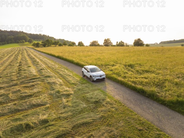 Car driving on a country road through a varied landscape at sunset, Renault Megane, Deer E
