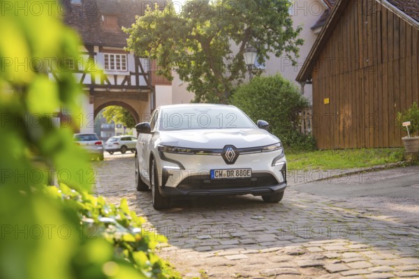 White car parked in an idyllic alley with half-timbered houses and bright sunshine, Renault Megane,