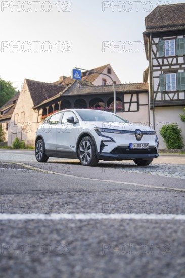 Modern car on an urban street, surrounded by historic half-timbered houses in the warm evening