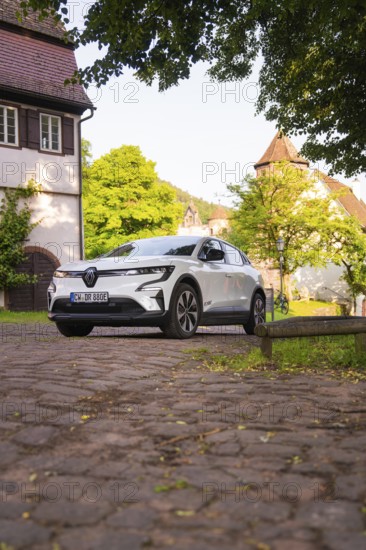 White car on cobblestones in a picturesque village, Renault Megane, Deer E Carsharing, electric