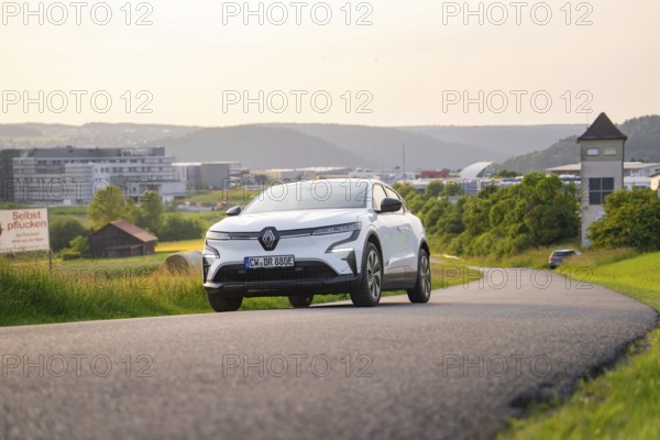 Car driving on a curvy road with modern city view in the background, Renault Megane, Deer E-
