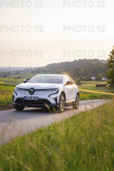 White car driving on a country road in the evening sunshine, Renault Megane, Deer E- Carsharing,