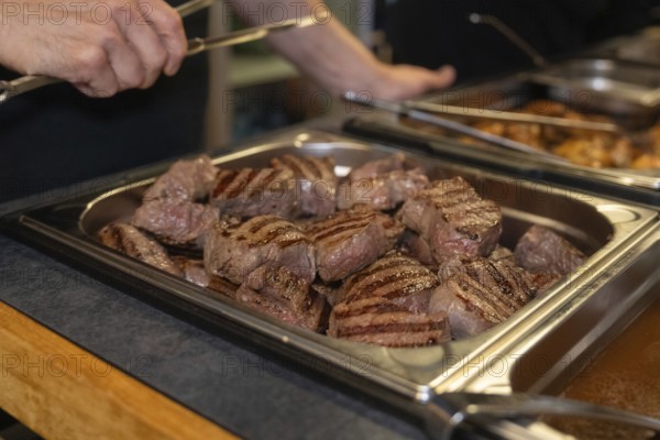 Several pieces of grilled meat in a buffet tray in a kitchen, ready to serve, event and wedding