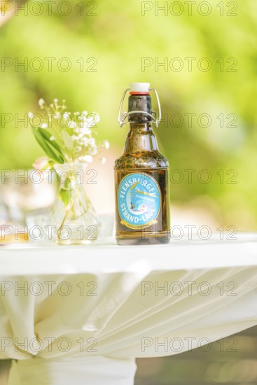 Table with a beer bottle and flower vase outside on a sunny day, event and wedding location Kloster