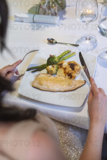 An elegant plate with fish, asparagus and broccoli on a white table, event and wedding location