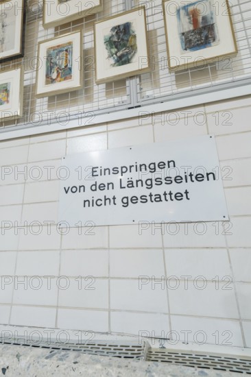 Sign on a tiled wall in a gallery with works of art on display, historical art exhibition in the