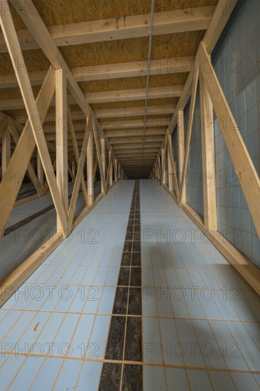 View into an attic with wooden struts and blue tiled floor leading into the distance, historical