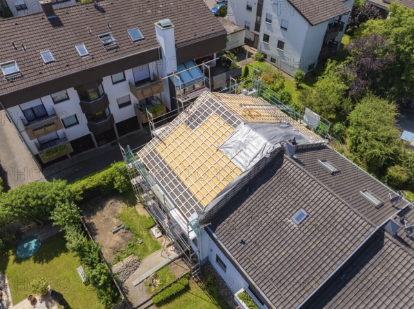 Several houses in the neighbourhood. A roof is under construction with scaffolding, sunny weather,