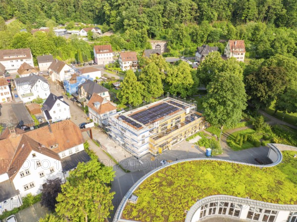 View of a residential area with a building site in the centre and green areas on some roofs,