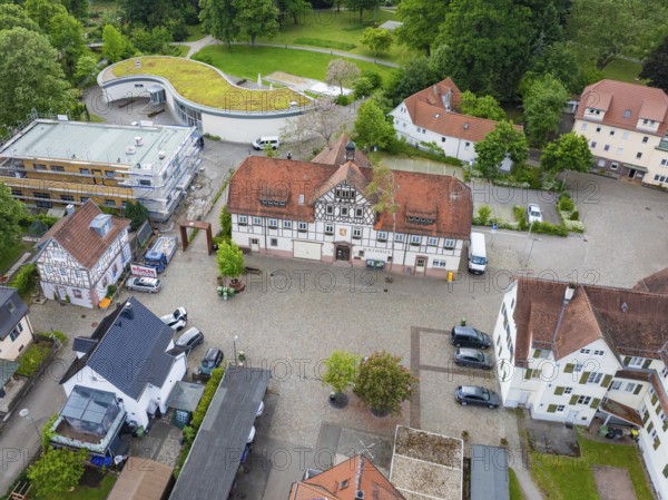Historic half-timbered houses with red tiled roofs surrounded by cobblestones and green spaces,