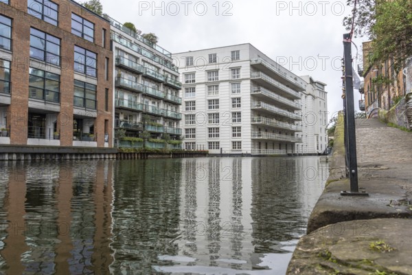 Modern and historic buildings reflecting in the calm waters of regent's canal in the city of london