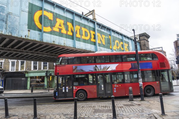 Iconic red double decker bus driving through camden town in london, under the bridge with the