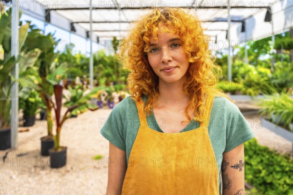 Confident young female gardener working in a vibrant greenhouse, surrounded by thriving plants and
