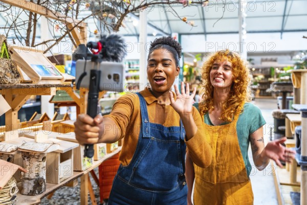 Two happy saleswomen waving at the camera while filming a video for social media marketing in a pet