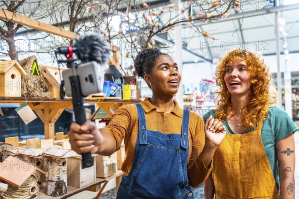 Two young women working in a garden center filming a video for social media using a smartphone with