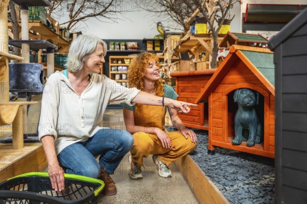 Pet shop worker assisting a customer with a shopping basket, pointing out various dog kennels and
