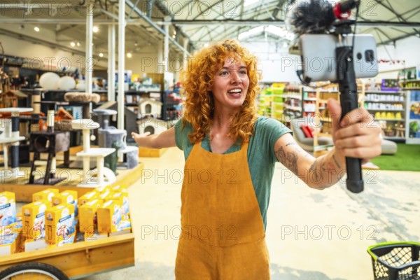 Young saleswoman filming a video for social media with a smartphone and microphone, showing pet