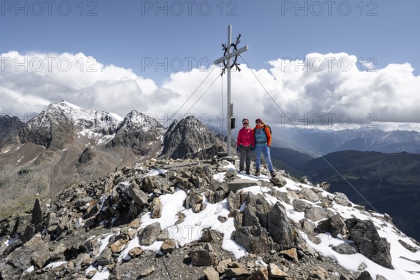 Two female mountaineers on the summit of the Keeskopf with summit cross, behind them summit of the