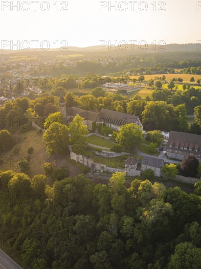 Aerial view of a monastery surrounded by dense vegetation at sunset, event and wedding location