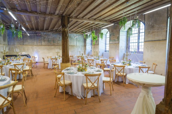 Rustic wedding setting with round tables and natural lighting through windows, event and wedding