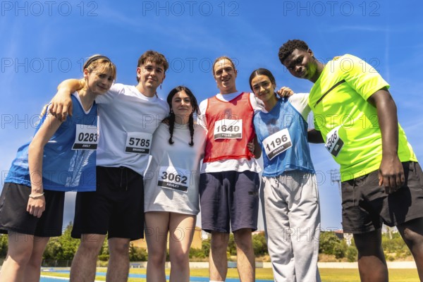 Group of young athletes embracing after a track and field competition, showing sportsmanship and