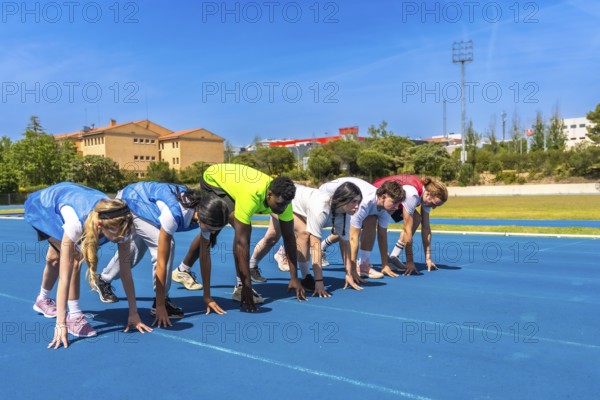 Diverse group of athletes ready to start a race on a blue running track, embodying competition and