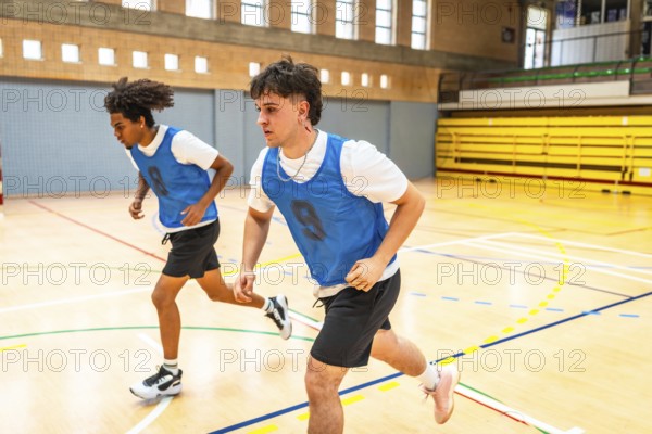 Two basketball players running on the court during training, practicing their speed and agility