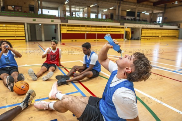 Basketball players taking a break on the court, drinking energy drinks, and recovering after an