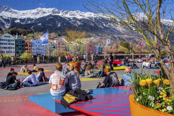 Sun-seekers on the market square on the banks of the Inn in front of the Nordkette mountain range