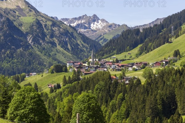 The mountain village of Mittelberg with its church nestled in a wooded valley landscape in