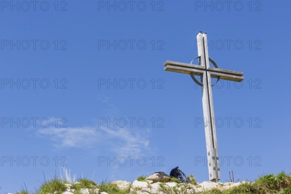 Summit cross of the Kuhgehrenspitze in Mittelberg rises in front of a bright blue sky in