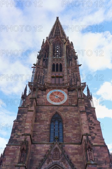 Freiburg Minster, Gothic church tower made of red stone with clock in front of a blue sky, Freiburg