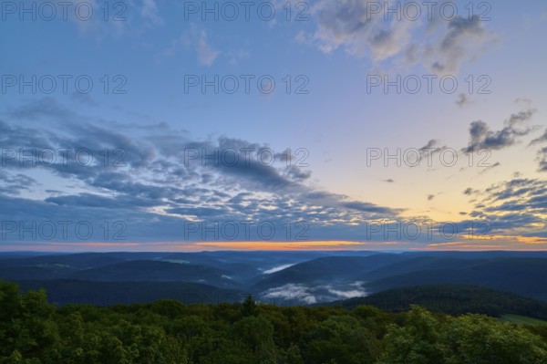 Wide landscape with wooded hills at dawn, peaceful sky with cloud formations, Katzenbuckel,