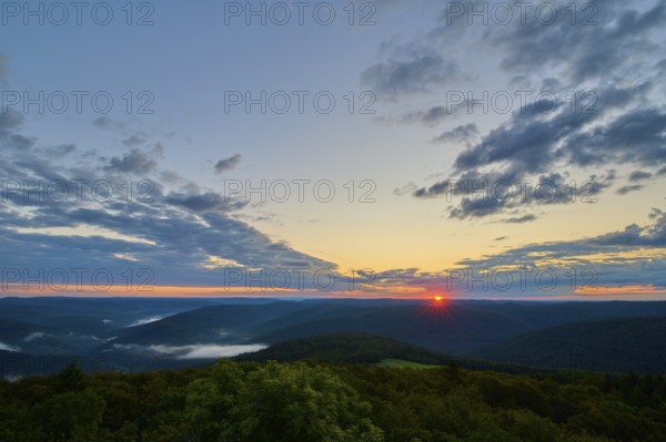 Sunrise over a forest landscape with vivid sky and clouds, warm colours of the morning,
