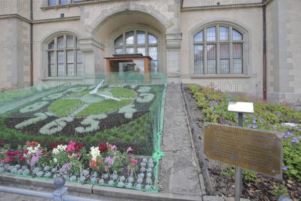 Flower clock made of blooming flower-bed with flower bed, clock face, garden art, information board
