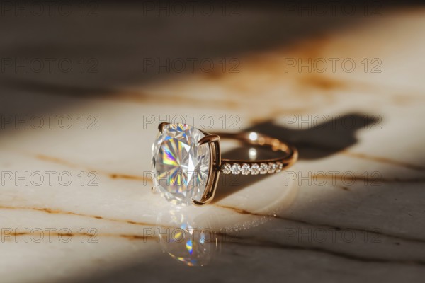 Close-up of diamond ring on polished marble surface with warm light and shimmering brilliance.