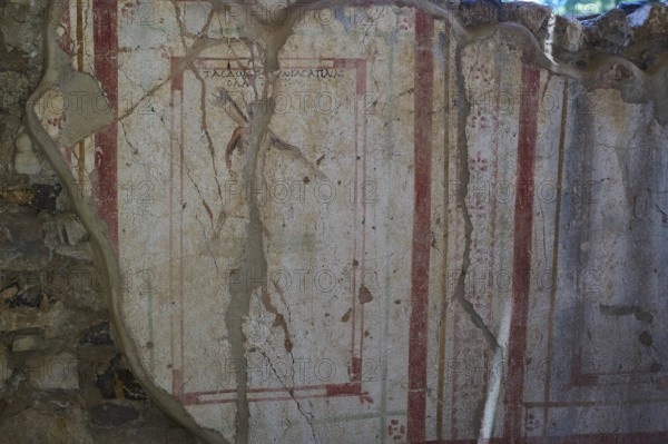 Weathered fresco with red decorative elements on ancient wall, Archaeological site, House of Beluga