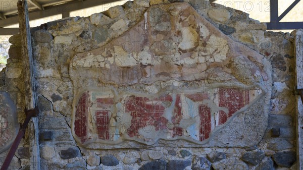 Ancient worn wall remnant with red drawings on stone wall, Archaeological site, House of Europe,