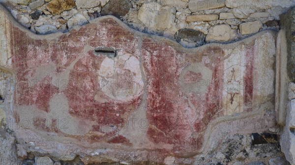 Decorated ancient wall fragment with red elements and traces of weathering, Archaeological Site,