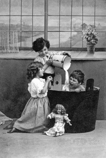 1910 Child being bathed by children, Two children playing in a black bathtub with dolls, Historical
