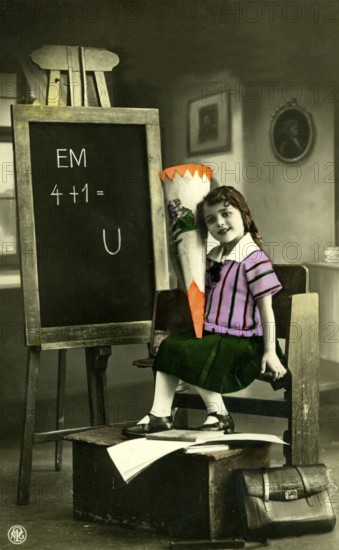 1920 A girl's first day at school, child with a sugar cone in front of a blackboard in a vintage