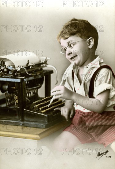 Boy at typewriter, 1920, Boy with glasses playing happily at an old typewriter, he seems to be